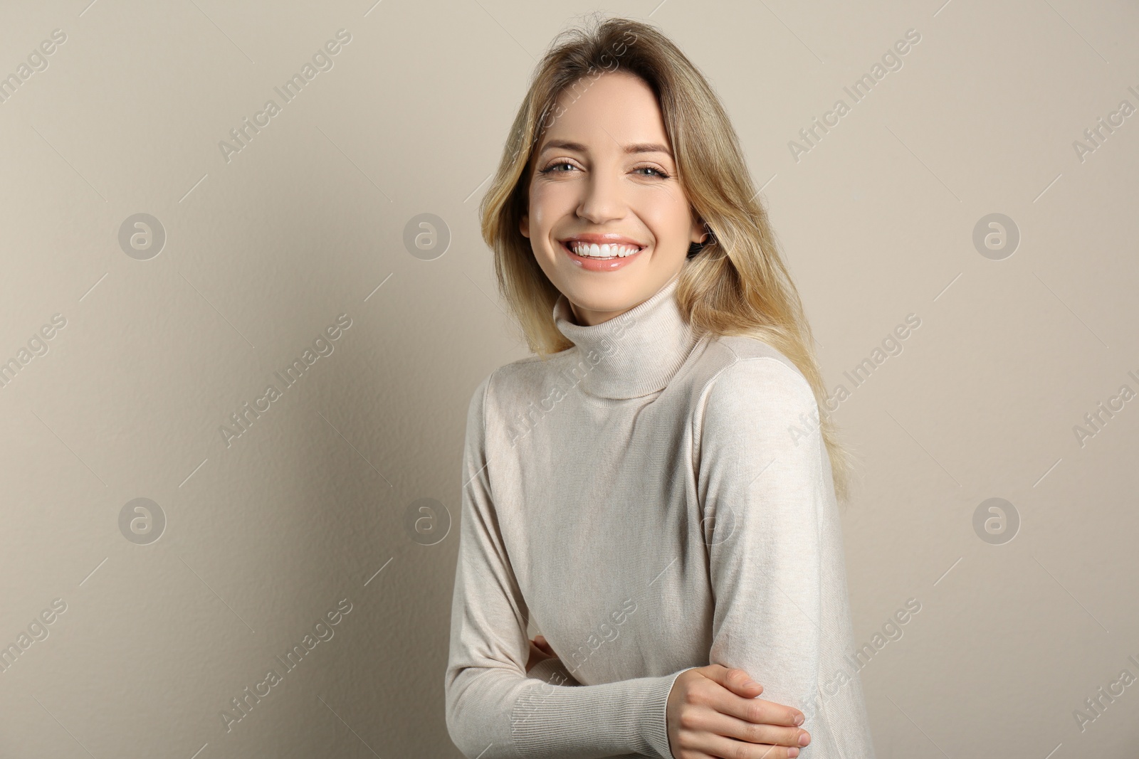 Photo of Portrait of happy young woman with beautiful blonde hair and charming smile on beige background