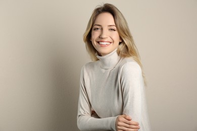 Photo of Portrait of happy young woman with beautiful blonde hair and charming smile on beige background