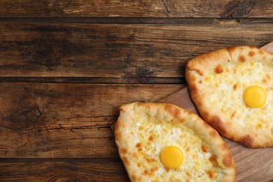 Photo of Fresh homemade khachapuri with cheese and egg on wooden table, top view. Space for text