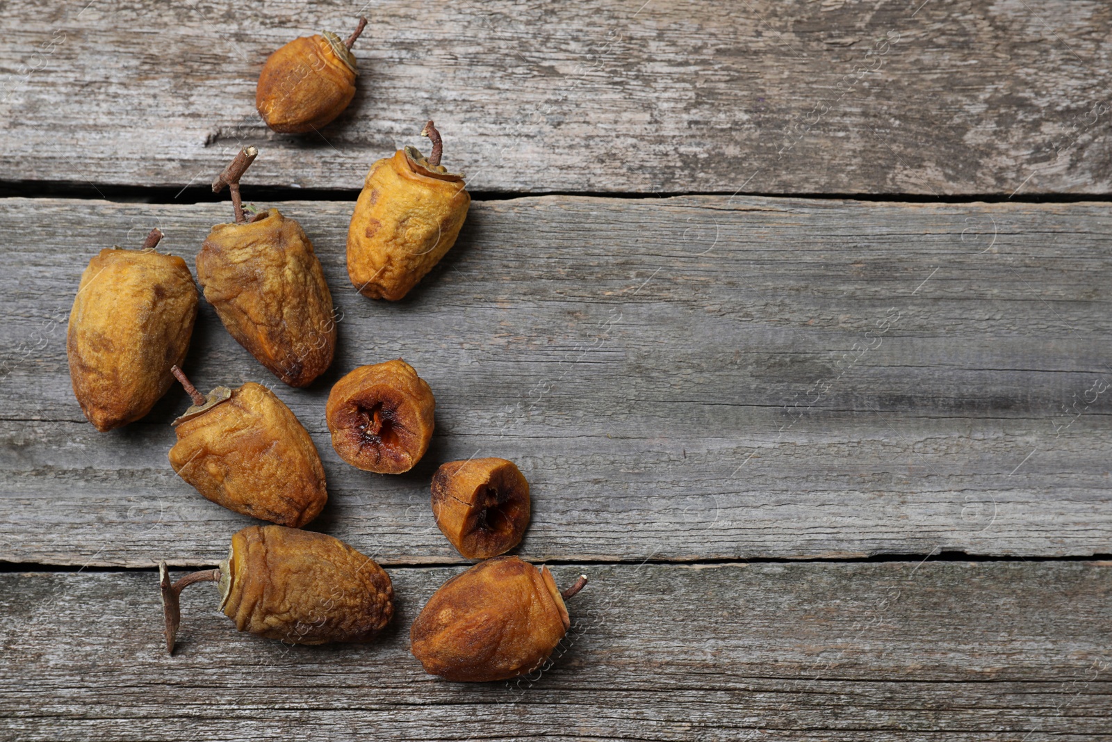 Photo of Many tasty dried persimmon fruits on wooden table, flat lay. Space for text