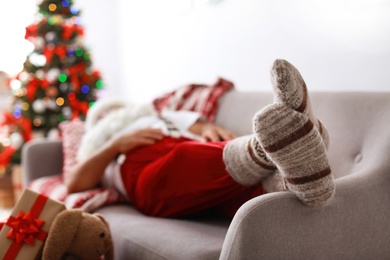 Photo of Authentic Santa Claus in warm socks sleeping on sofa indoors
