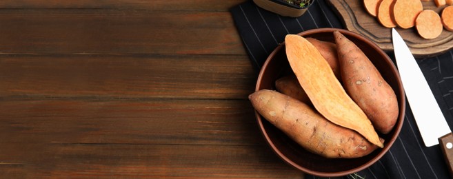 Cut and whole sweet potatoes on wooden table, flat lay with space for text. Banner design