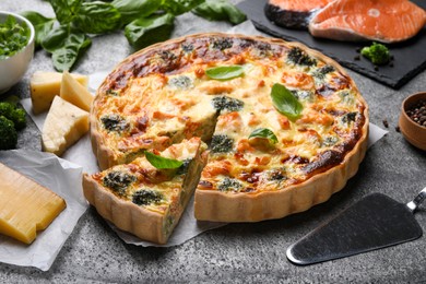 Photo of Delicious homemade quiche and ingredients on gray table
