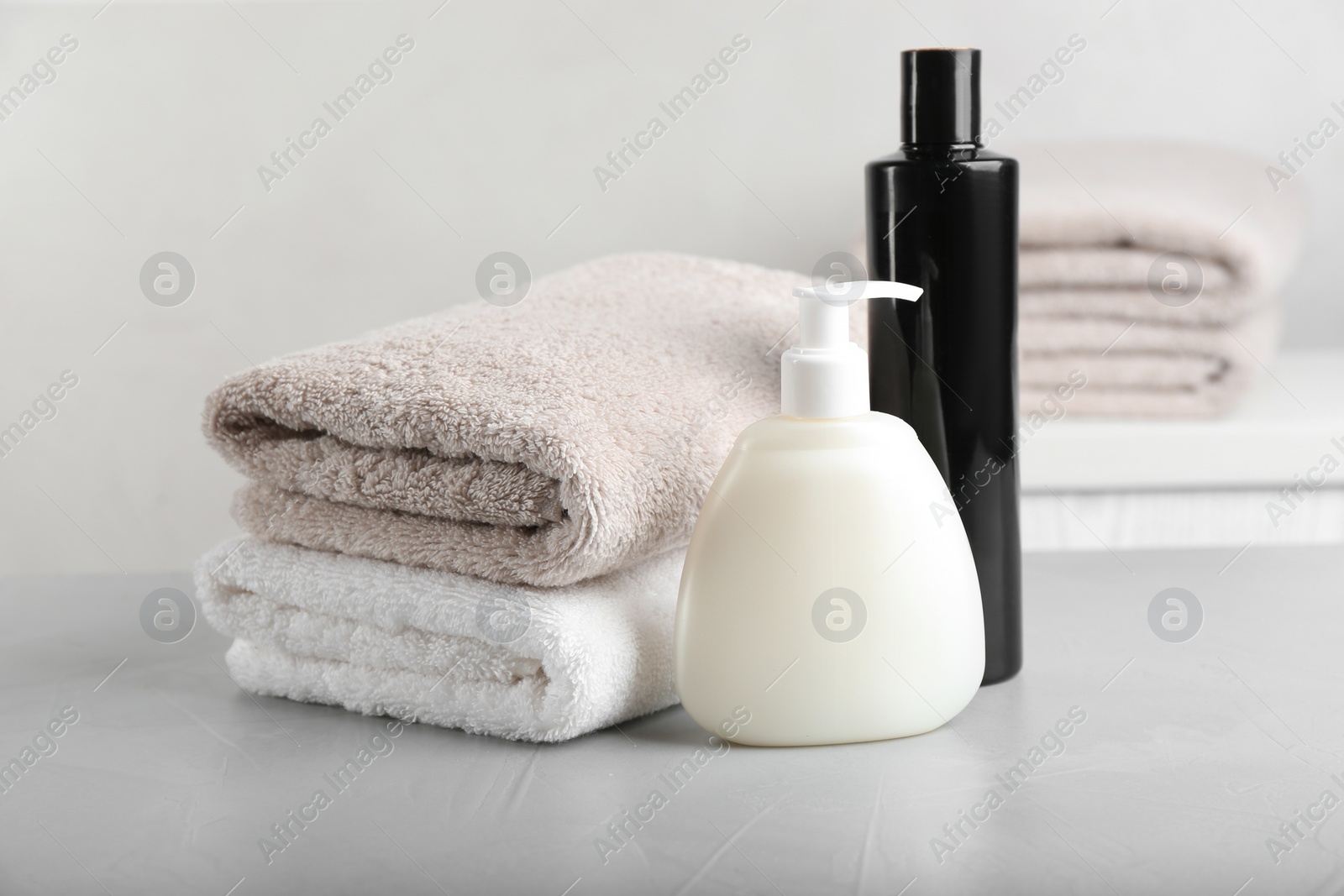 Photo of Fresh towels and toiletries on light grey stone table