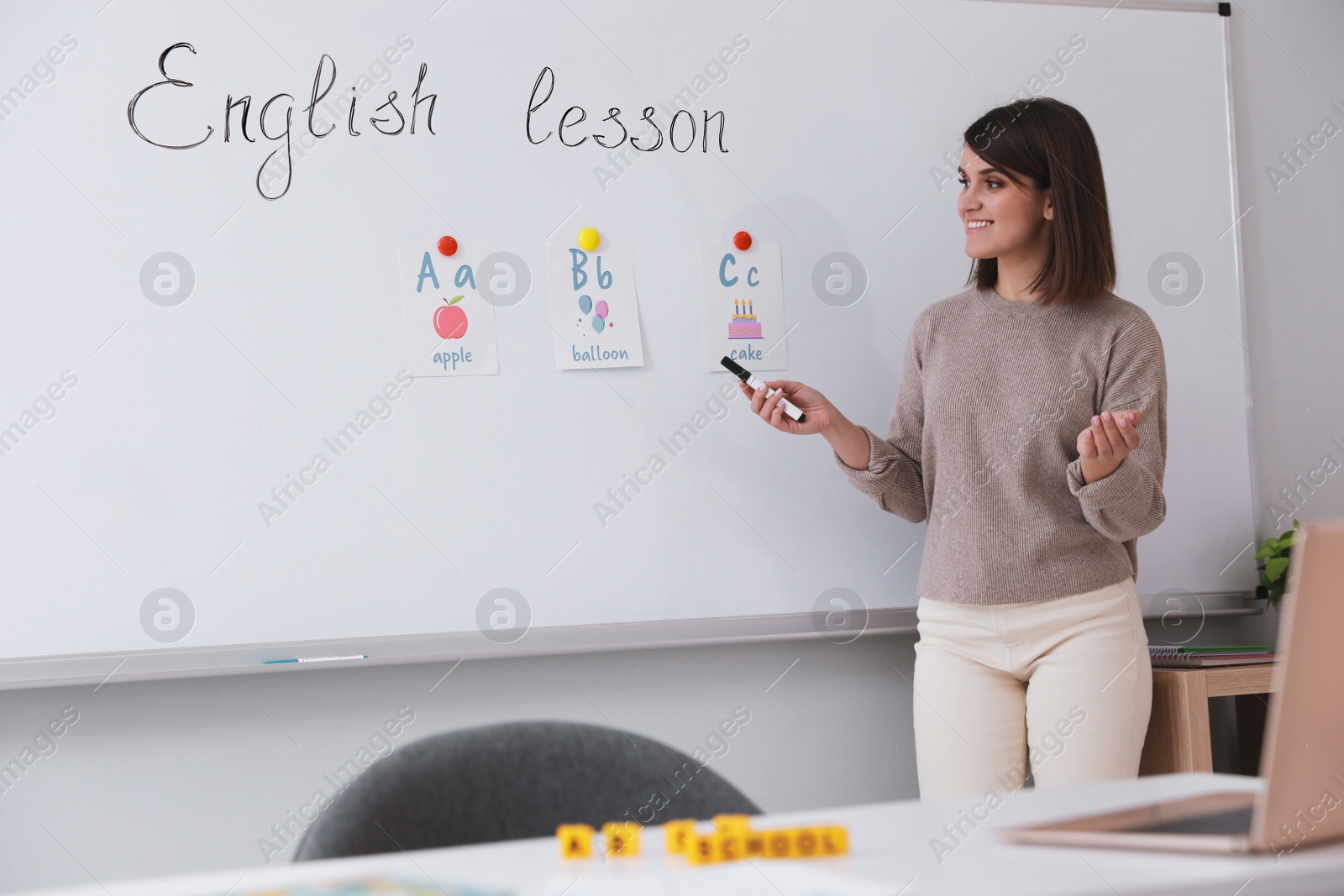 Photo of Happy female English teacher giving lesson indoors. Early childhood education
