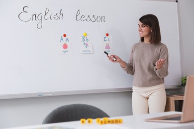 Photo of Happy female English teacher giving lesson indoors. Early childhood education