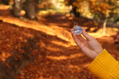 Photo of Traveler searching direction with compass in wilderness, closeup. Space for text