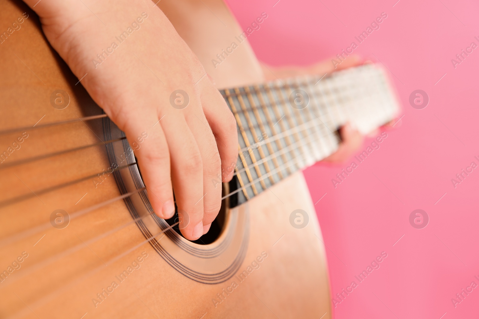 Photo of Little girl playing wooden guitar, closeup view