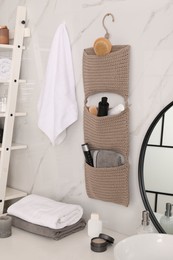 Photo of Knitted organizer hanging on wall in bathroom