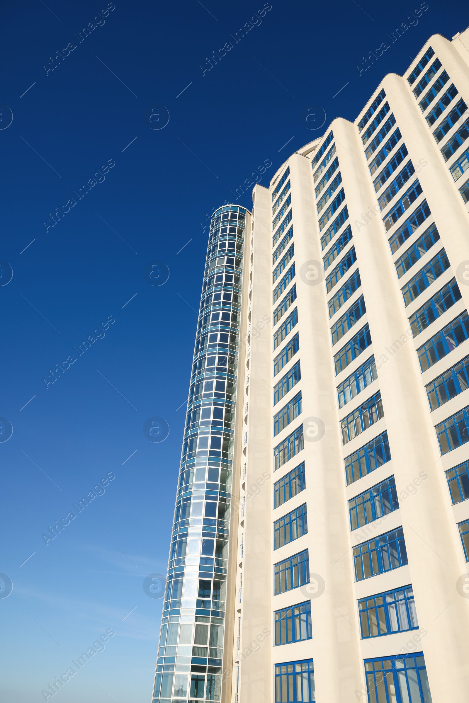 Photo of Beautiful skyscraper against blue sky on sunny day, low angle view