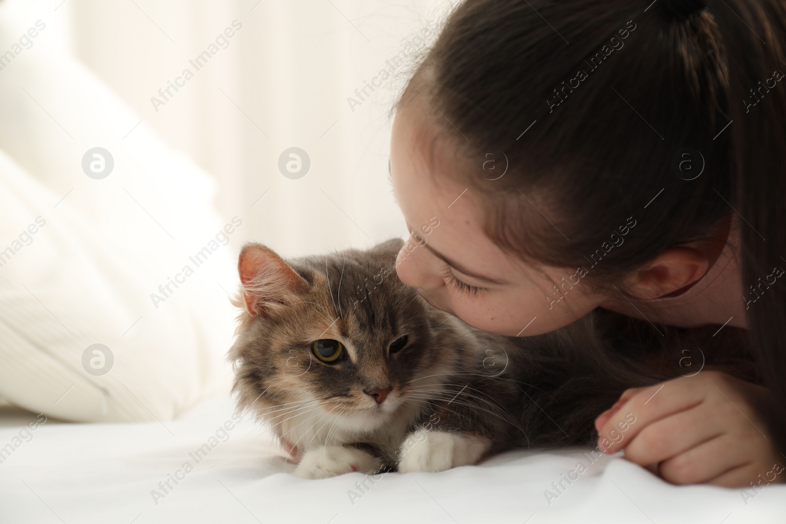 Photo of Cute little girl with cat lying on bed at home. First pet