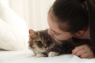 Cute little girl with cat lying on bed at home. First pet