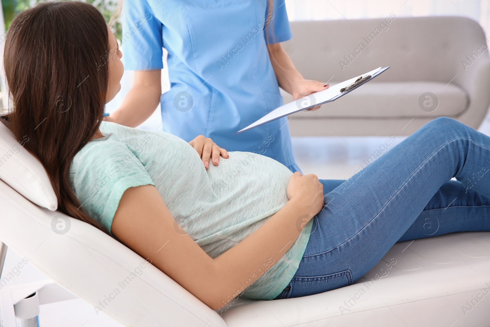 Photo of Young pregnant woman with her doctor in clinic