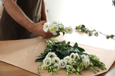 Photo of Florist making beautiful bouquet in workshop, closeup