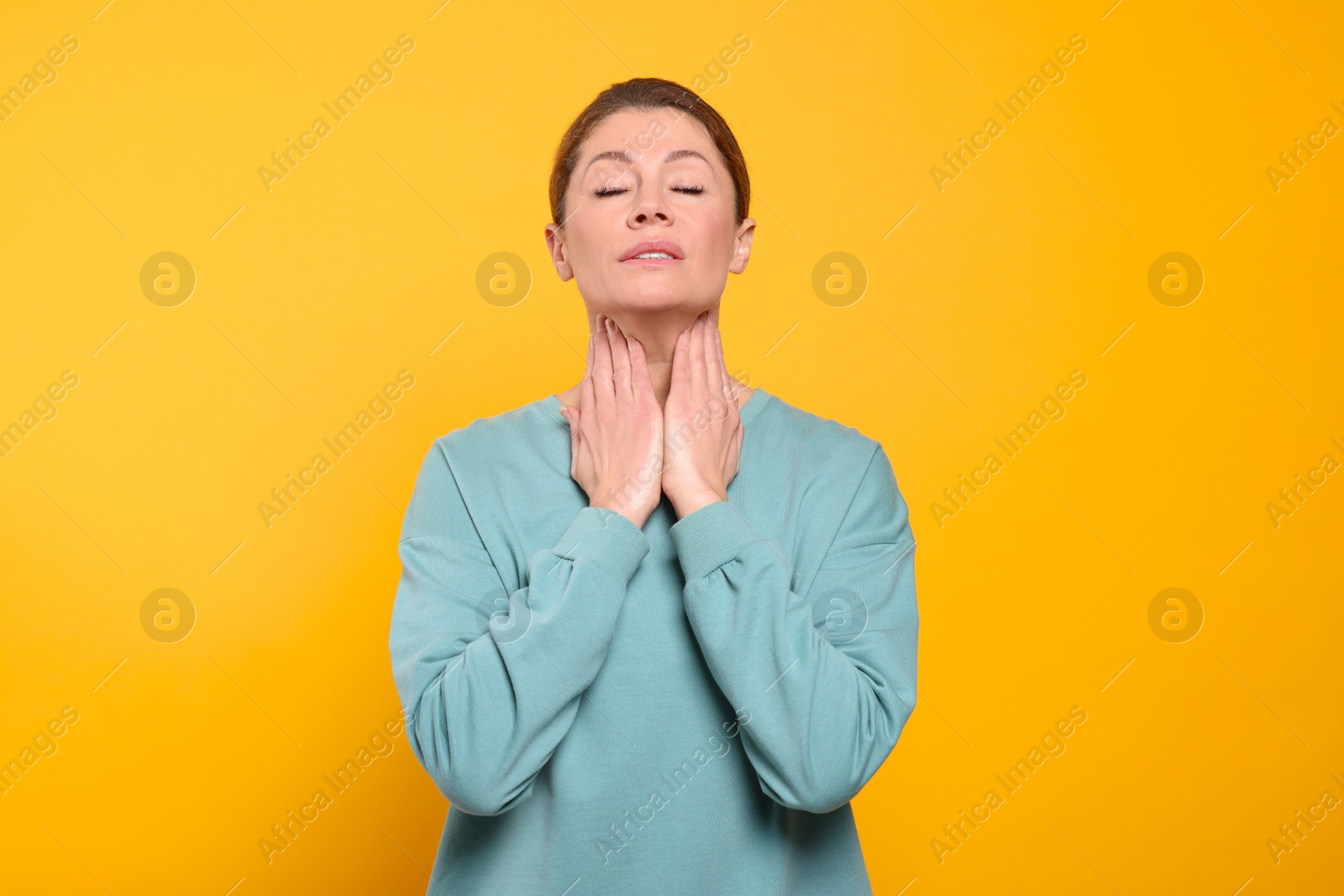 Photo of Woman suffering from sore throat on orange background