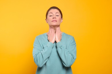 Photo of Woman suffering from sore throat on orange background