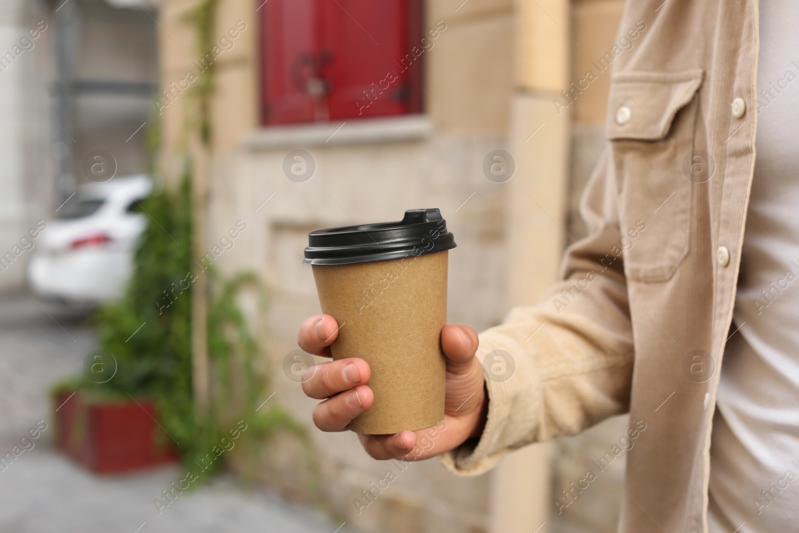 Photo of Coffee to go. Man with paper cup of drink outdoors, closeup. Space for text