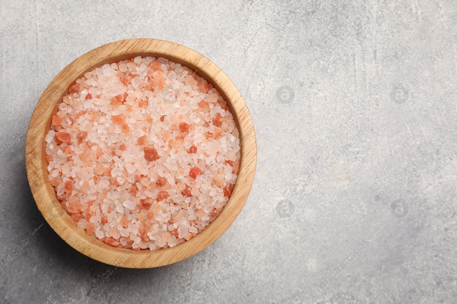 Photo of Bowl with natural sea salt on light grey table, top view. Space for text