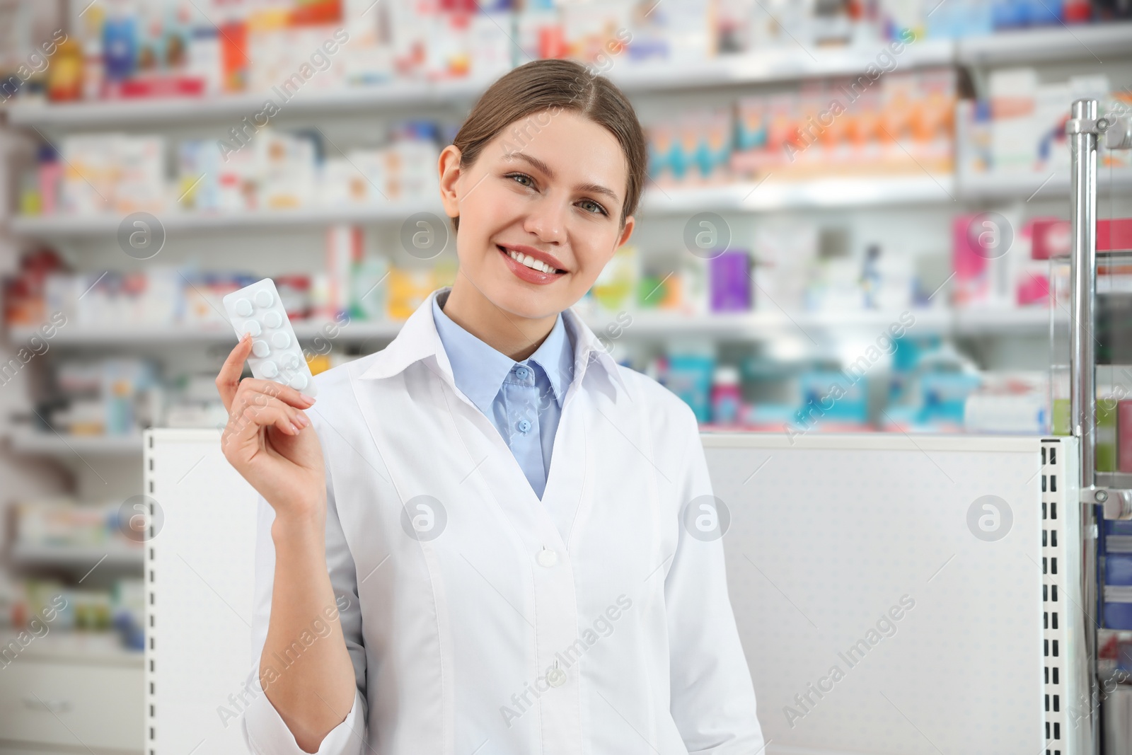 Photo of Professional pharmacist with pills in modern drugstore