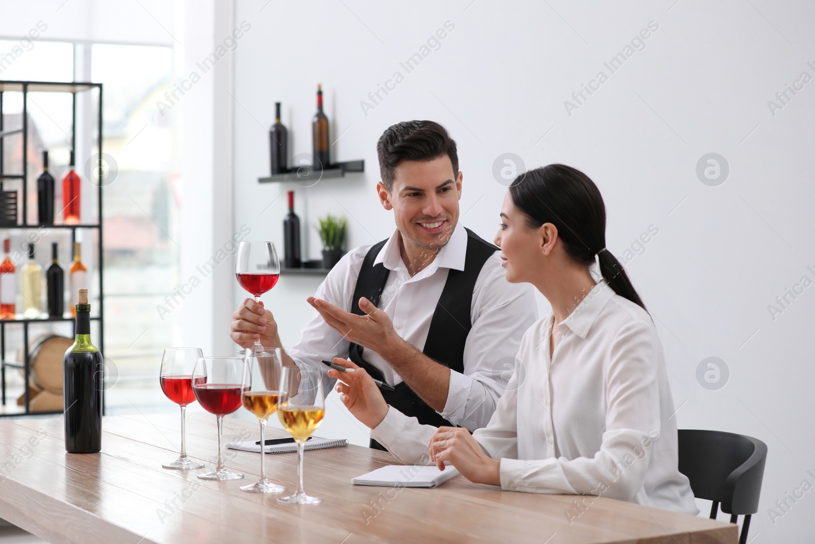 Photo of Sommeliers tasting different sorts of wine at table indoors