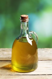 Photo of Jug of olive oil on wooden table against blurred background