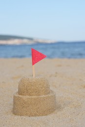 Photo of Beautiful sand castle with red flag on beach near sea