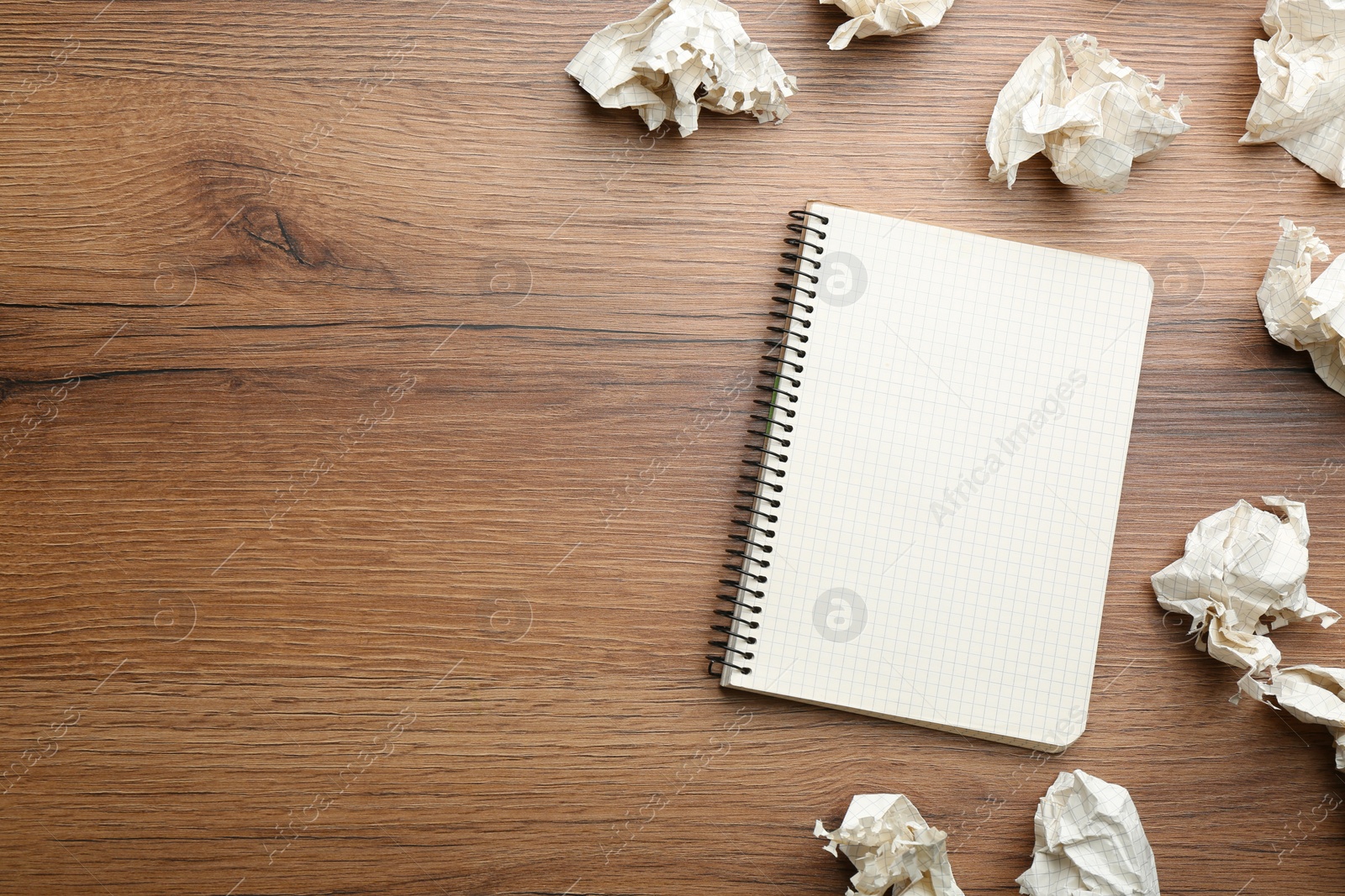 Photo of Notebook and crumpled sheets of paper on wooden background, flat lay. Space for text