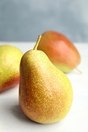 Photo of Ripe juicy pear on white wooden table against blue background