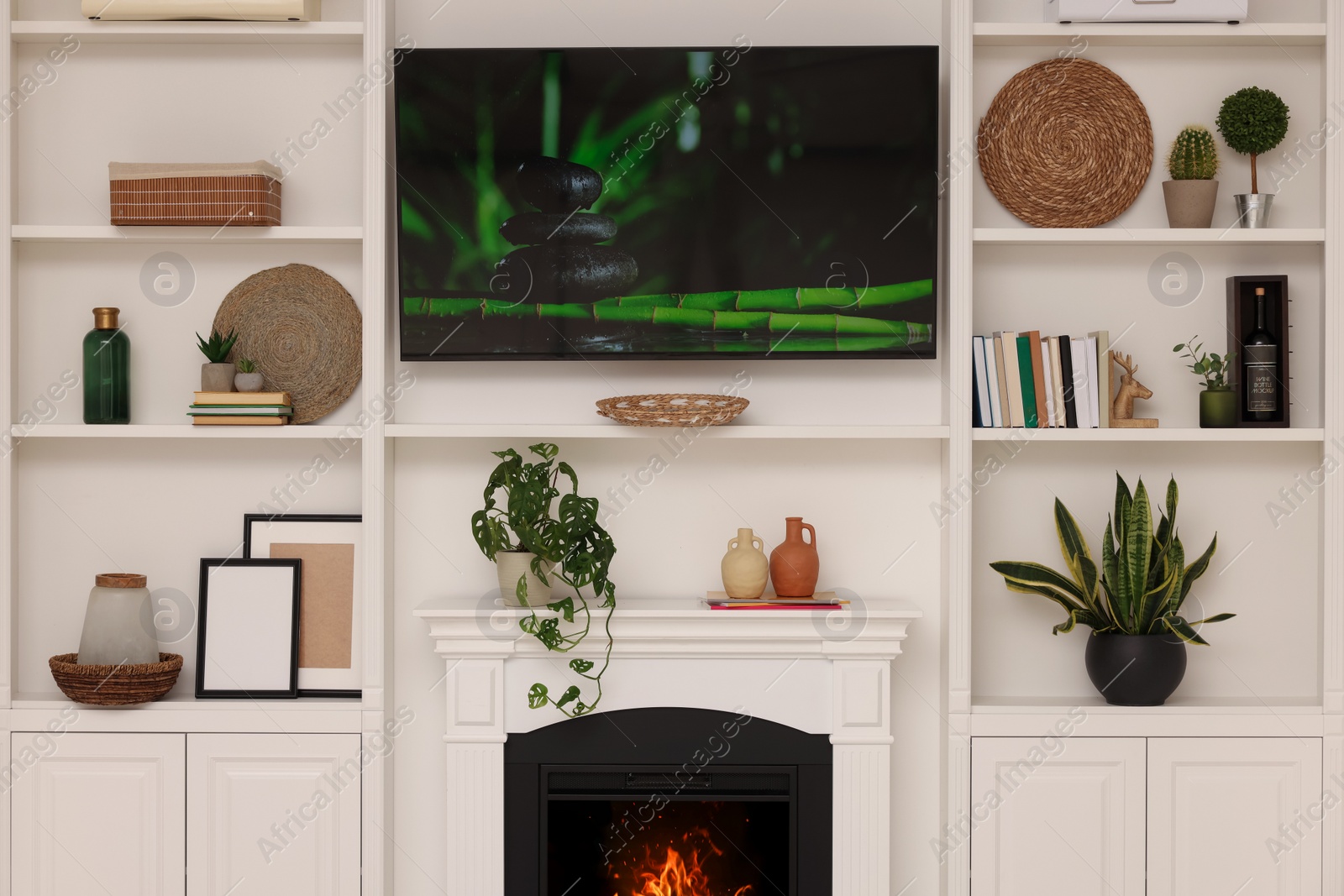 Photo of TV, fireplace and shelves with different decor in room. Interior design