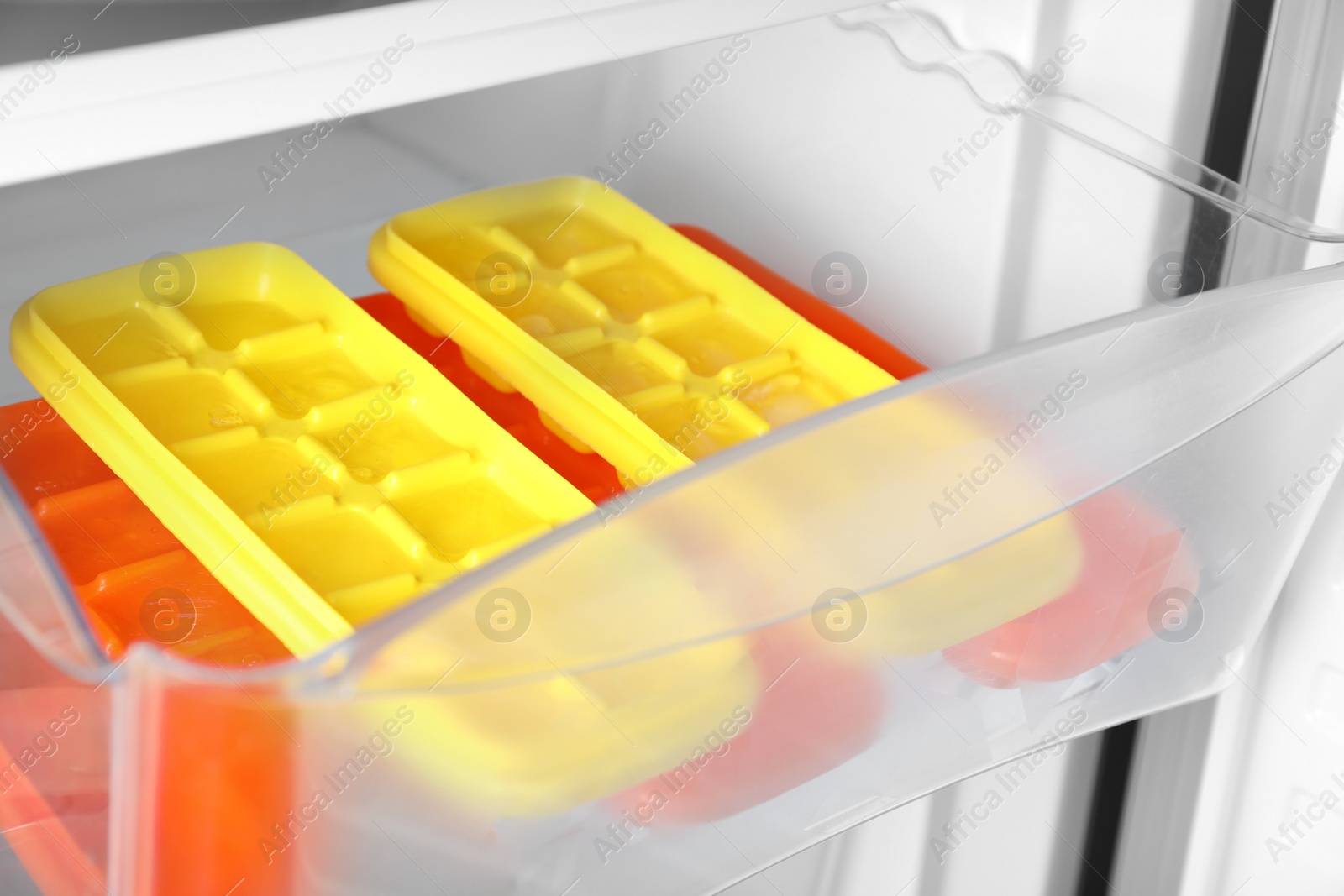 Photo of Different plastic ice cube trays in fridge