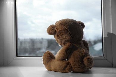 Photo of Cute teddy bear on windowsill indoors, back view. Space for text
