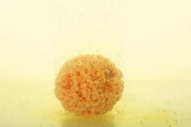 Yellow bath bomb in water on white background