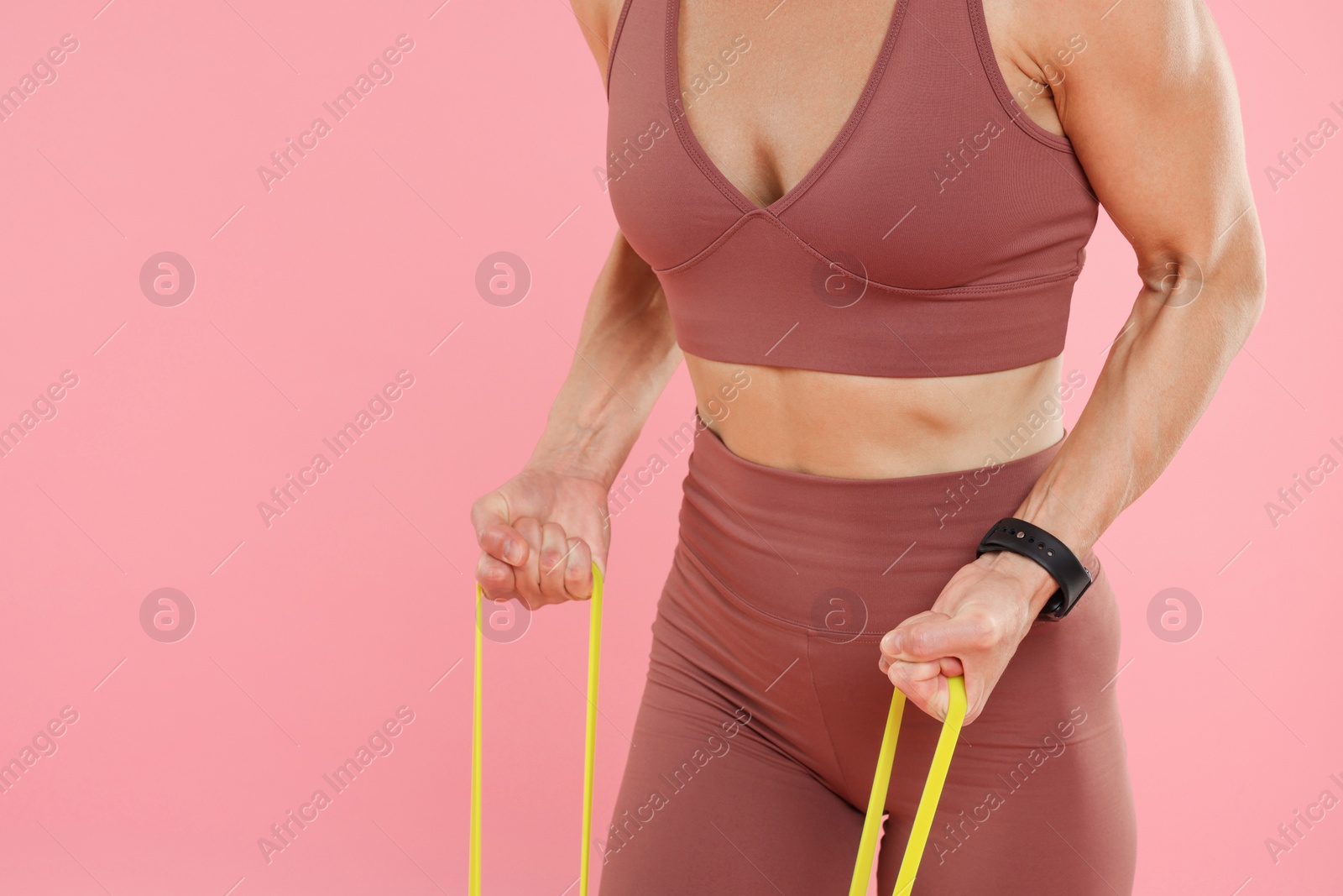 Photo of Woman exercising with elastic resistance band on pink background, closeup. Space for text