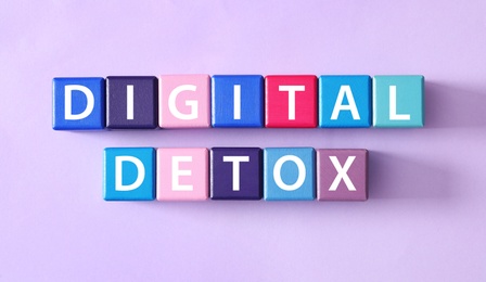Color cubes with words DIGITAL DETOX on violet background, flat lay