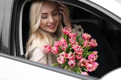 Happy young woman with beautiful bouquet in car