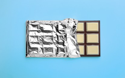 Tasty chocolate bar on light blue background, top view