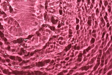 Photo of Rippled surface of clear water on bright pink background, top view