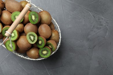 Photo of Fresh ripe kiwis in metal basket on grey table, top view. Space for text