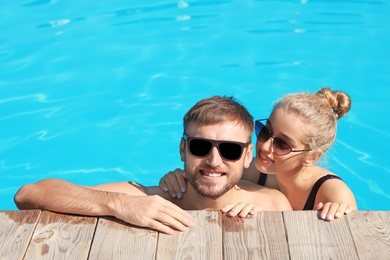 Photo of Happy young couple in swimming pool at resort