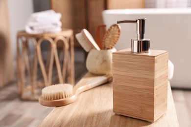 Photo of Dispenser of liquid soap and brush on wooden table in bathroom, space for text