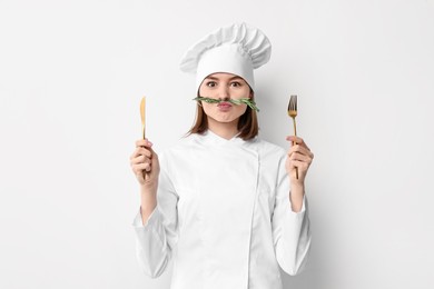 Photo of Professional chef with rosemary and cutlery having fun on light background