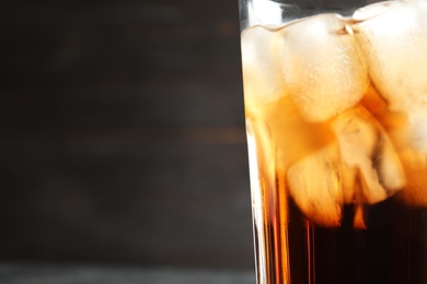 Photo of Glass of tasty refreshing cola with ice cubes on dark background, closeup. Space for text