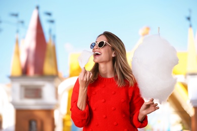 Photo of Young cheerful woman having fun with  cotton candy in amusement park
