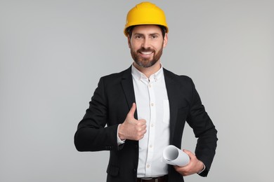 Photo of Architect in hard hat with draft on gray background