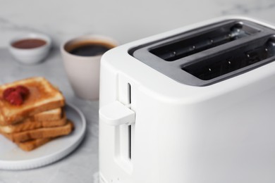 Photo of Toaster and roasted bread on table, closeup