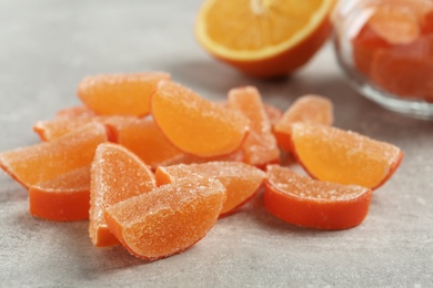 Photo of Tasty orange jelly candies on grey table, closeup