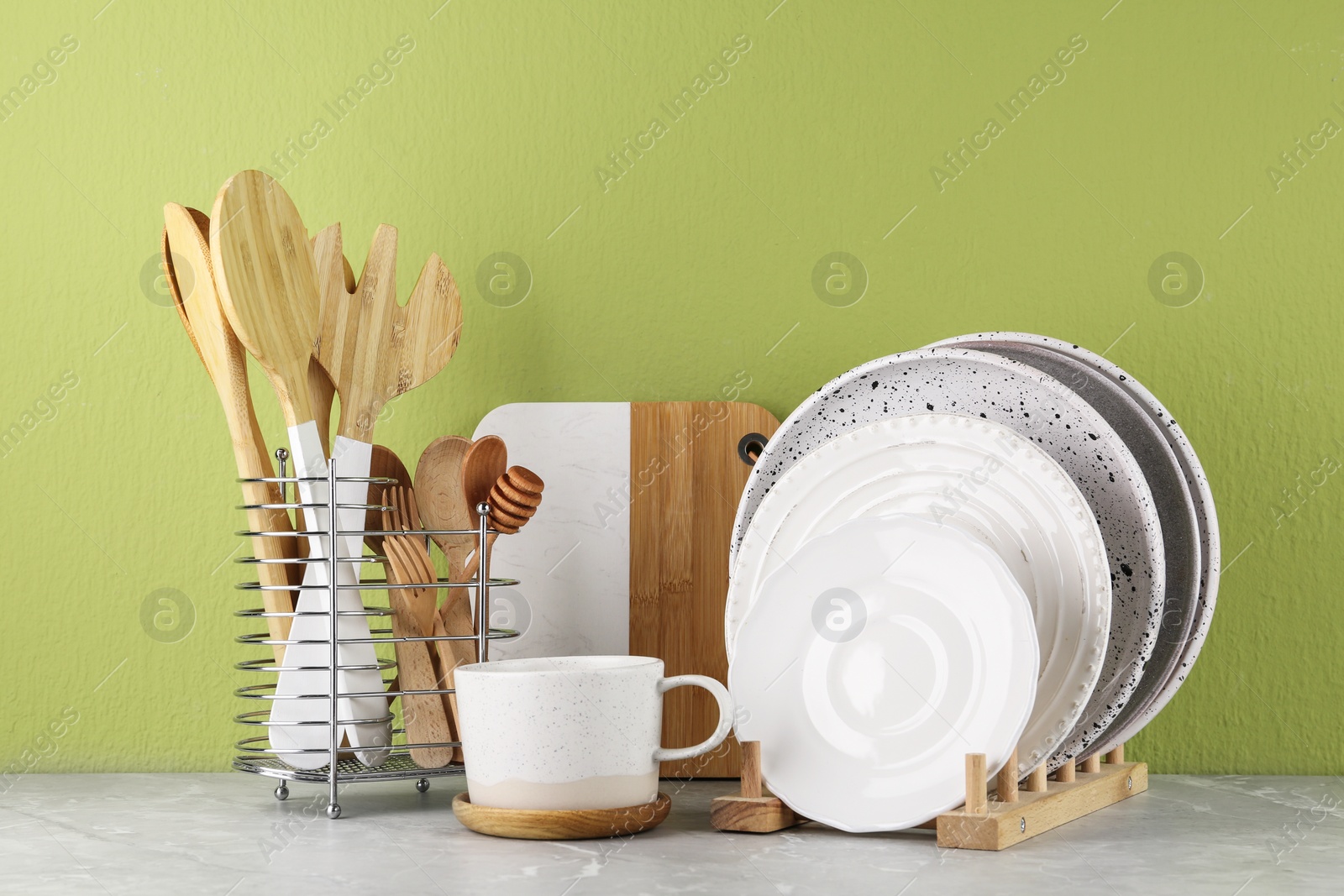Photo of Set of kitchenware on marble table near green wall. Modern interior design