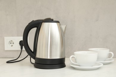 Photo of Electric kettle and cups on counter in kitchen