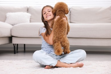 Photo of Little child with cute puppy on carpet at home. Lovely pet