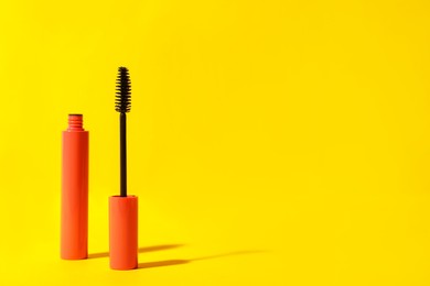 Photo of Mascara on yellow background, space for text. Makeup product
